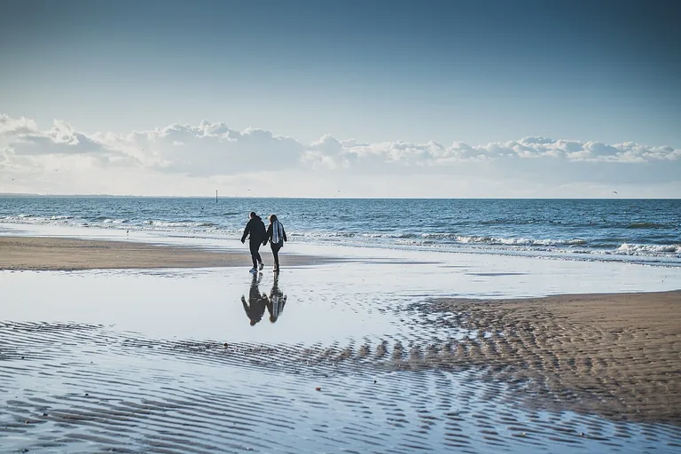 Promeneurs et reflets sur la plage de Cabourg à marée basse.
